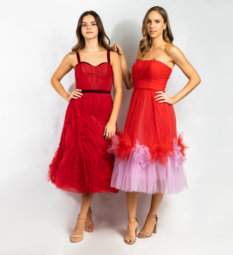 Par de mujeres juntas con vestidos rojos con rosa